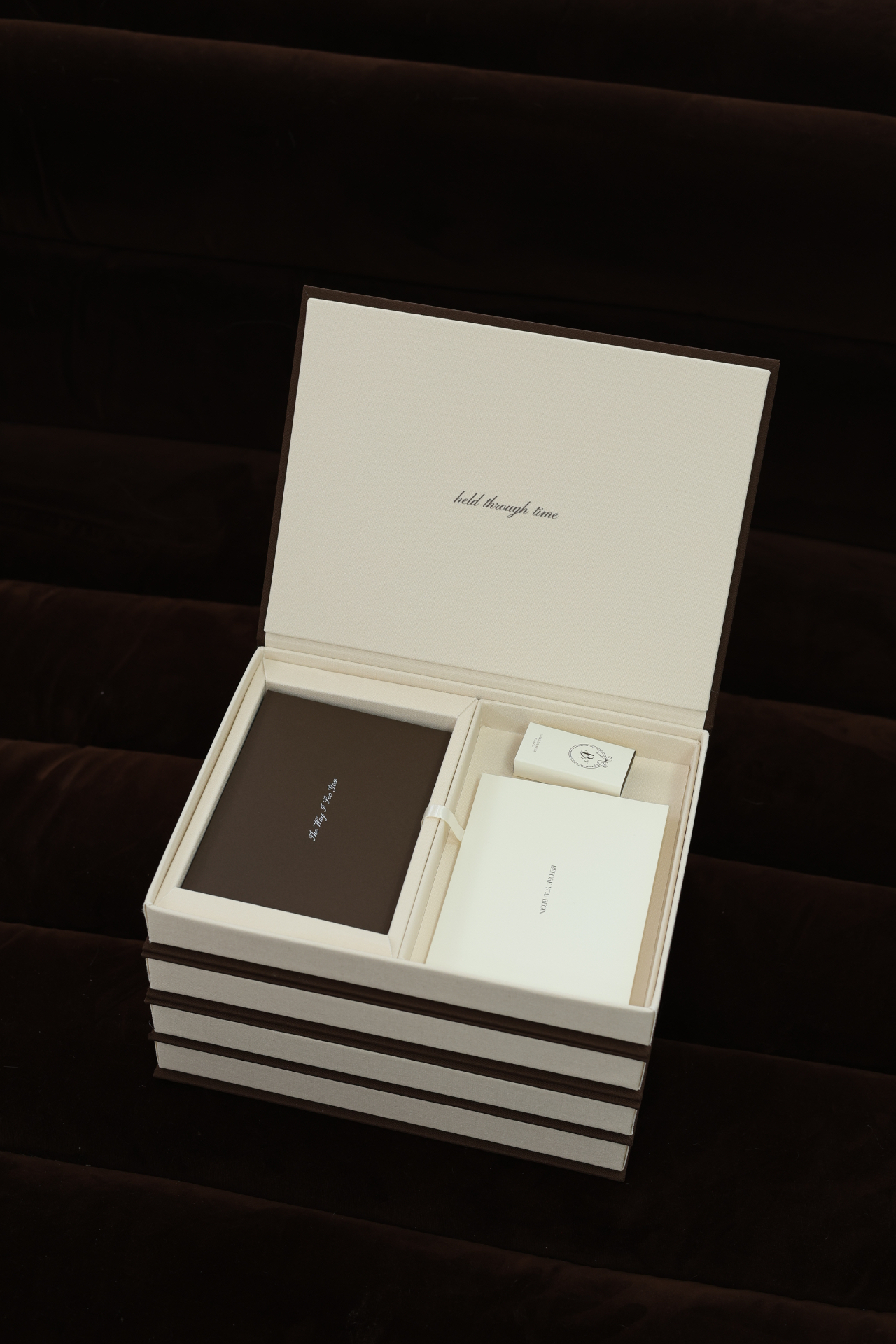The open Keepsake Collection resting on a dark chocolate velvet sofa, held through time on the inside of the lid